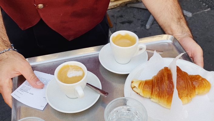 Typical Italian waiter holding a tray with cups of espresso cornetto and water glasses in Rome Lazio