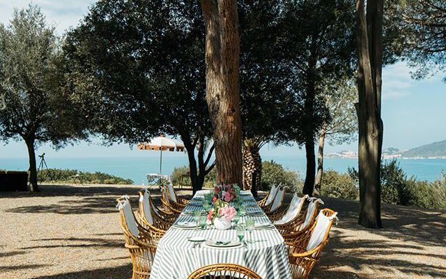 Vintage wooden table and chairs outdoors surrounded by trees and sea background of Villa Talamo in Tuscany Italy
