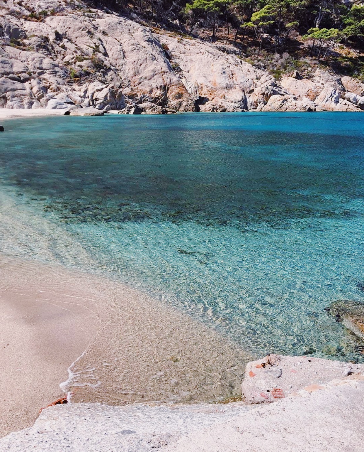 Blue clear sea water and rocks viewed from a rock at Montecristo Tuscany in Italy