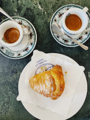 Espresso cups and italian pastry over colorful plates and blue counter in Napoli Campania