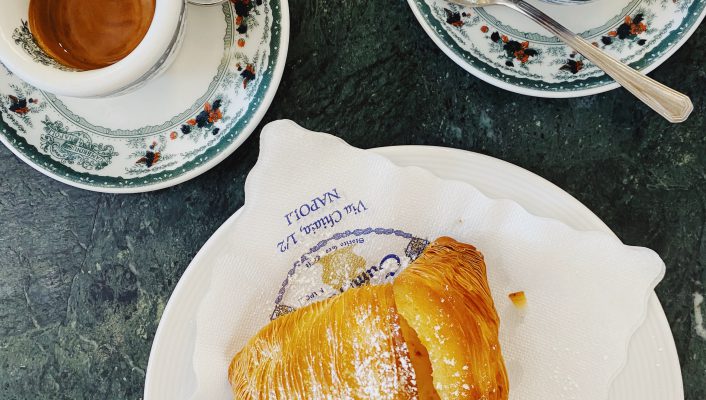 Espresso cups and italian pastry over colorful plates and blue counter in Napoli Campania