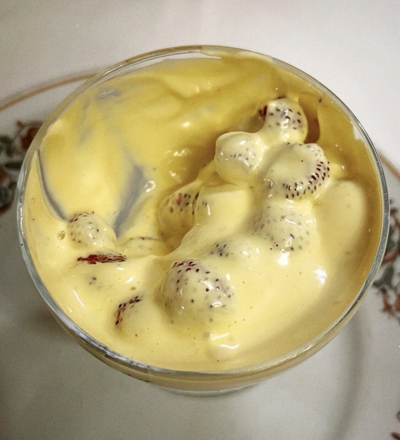 a cup filled with strawberries covered in a thick, yellowish zabaione cream