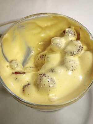a cup filled with strawberries covered in a thick, yellowish zabaione cream