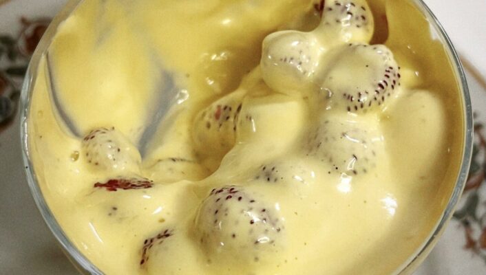 a cup filled with strawberries covered in a thick, yellowish zabaione cream