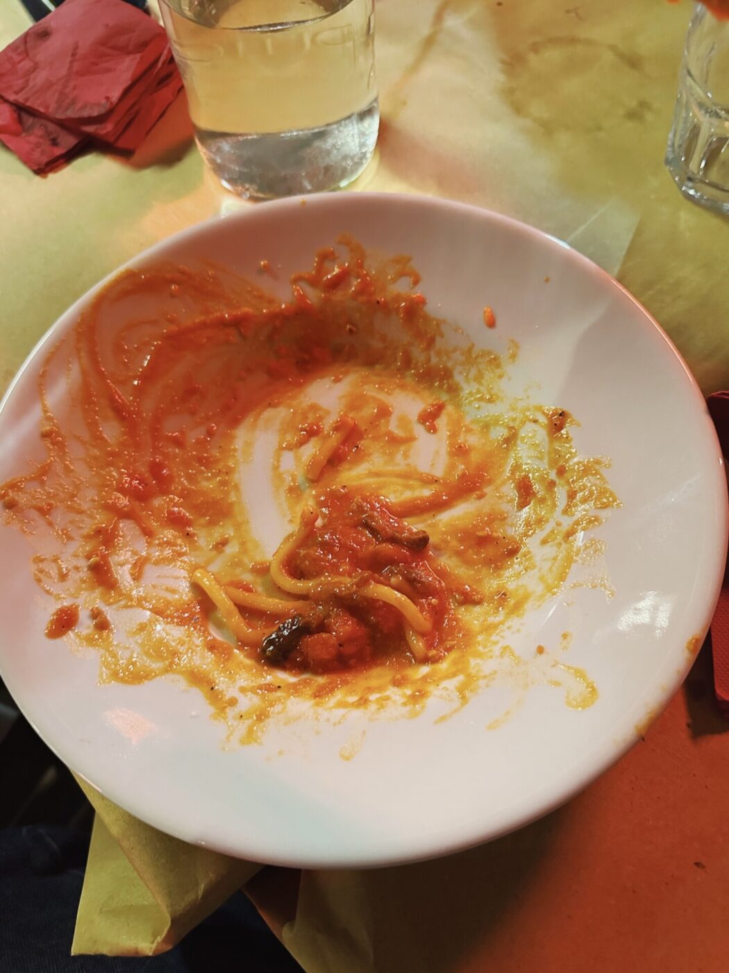 almost empty dish pf spaghetti with red sauce