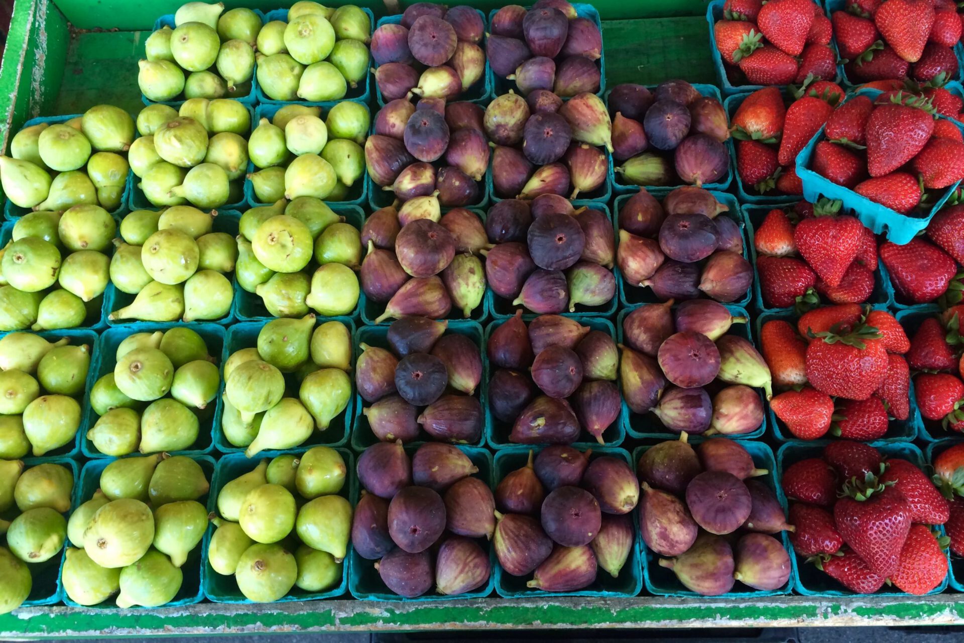 Market tray with green and black figs and strawberries blue boxes to sell
