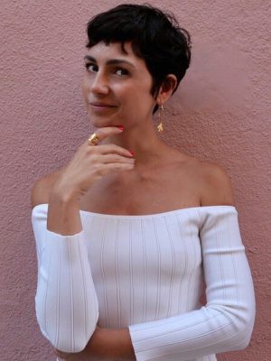 Eva Geraldine posing in front of a red wall white dressed