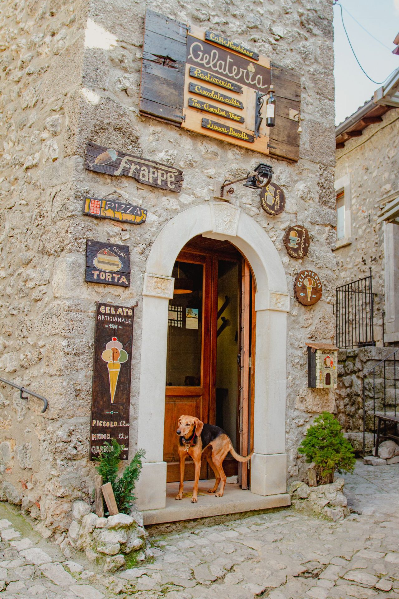 Italian Gelateria in antique building with signs and dog in the door in abruzzo in Italy