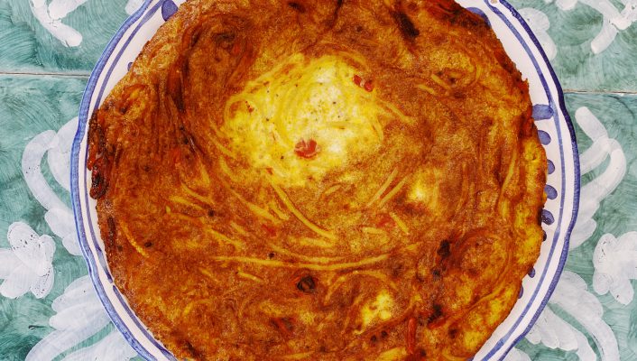 Frittata di pasta over blue ceramic plate and blue decorated background in Italy