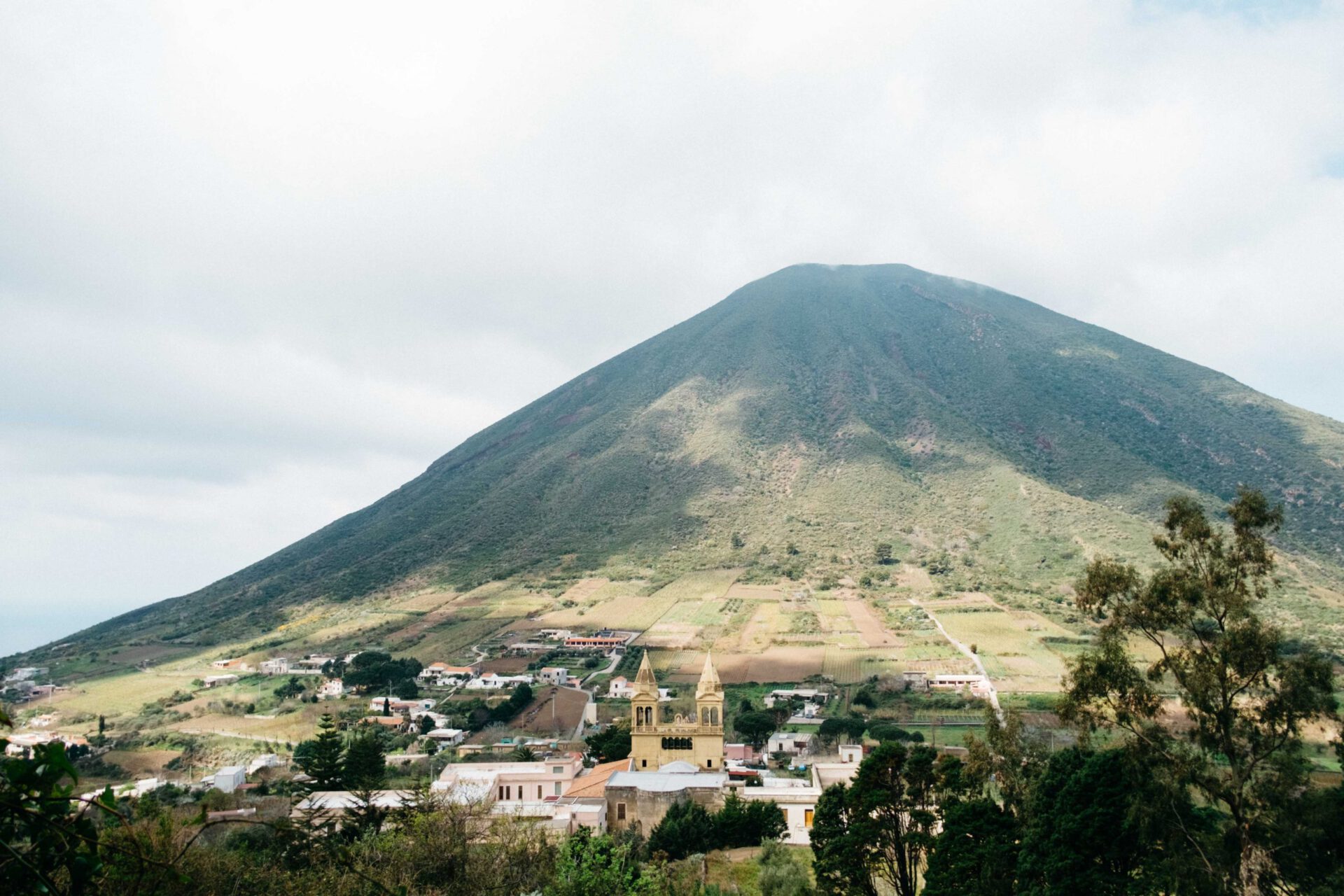 High green mountain with houses and church below in Salina Sicily in Italy