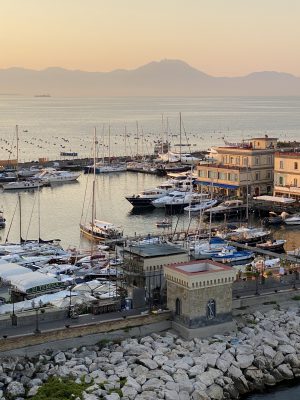 Port over the sea with boats rocks and mountains background sunset in Naples in Campania Italy