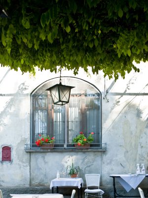 White tables and chairs under plants in front of white wall with window at Trattoria Al Laghett 1890 in Milan Lombardy in Italy