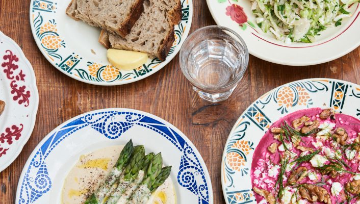 Colorful ceramic plates asparagus bread and salads from the book Towpath: Recipes and Stories by Laura Jackson and Lori De Mori