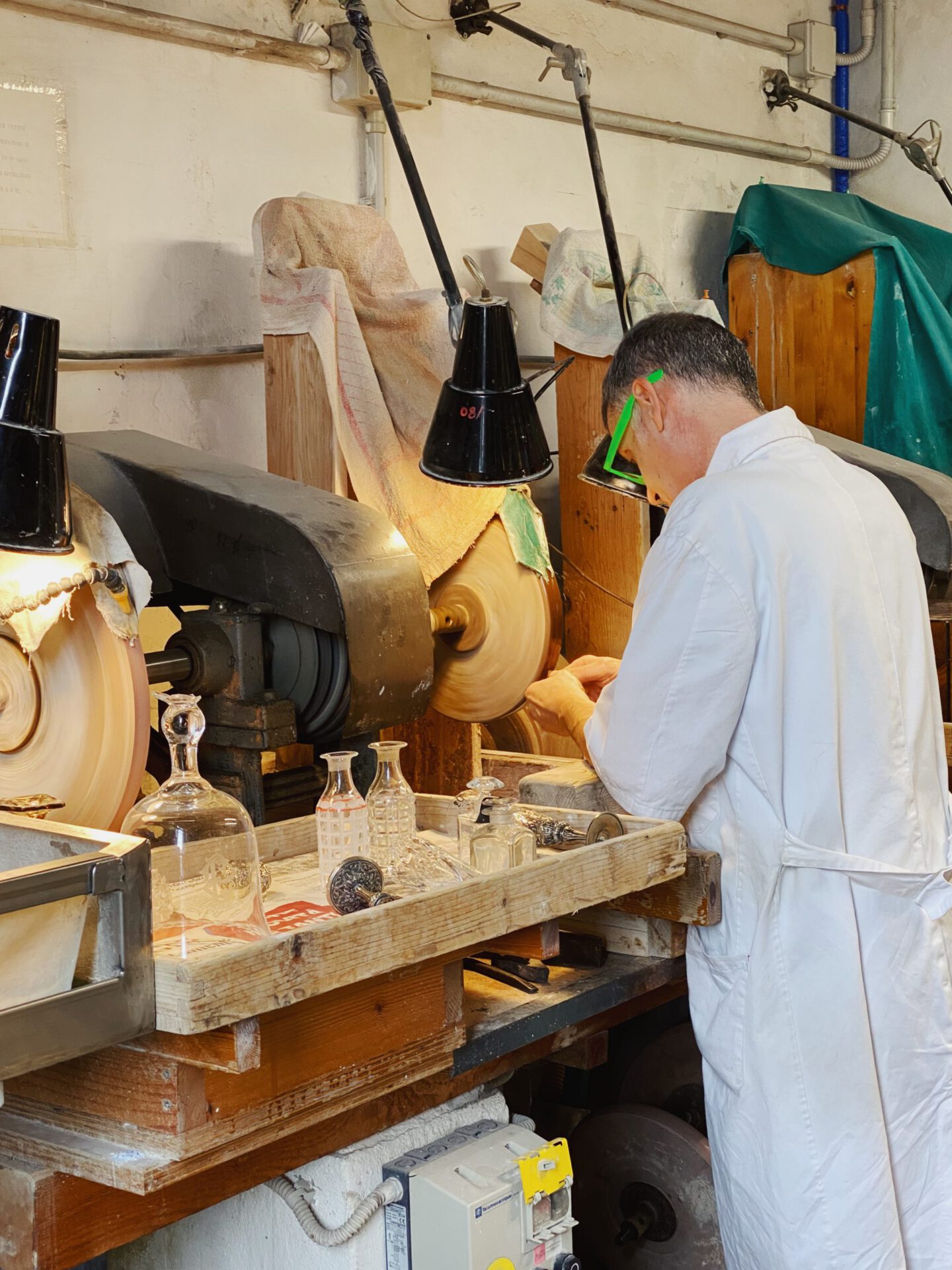 Man working a crystal piece over a polisher machine in glass and crystal fabric Moleria Locchi in Florence Tuscany in Italy