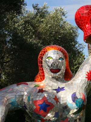 a woman in the Il Giardino dei Tarocchi made of silver mirrors holding a hand up