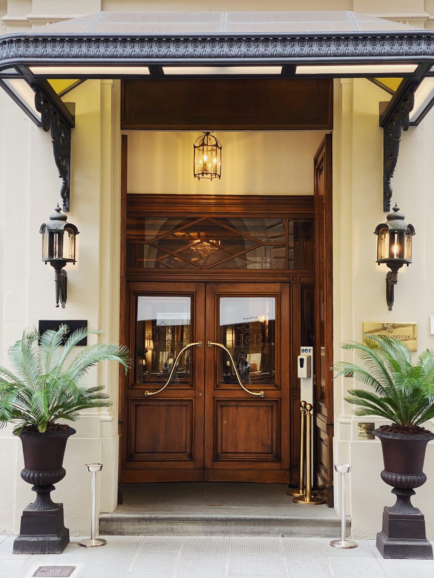 Entrance with wooden door luxury lamps and plants pots at the Helvetia & Bristol hotel in Florence Tuscany in Italy