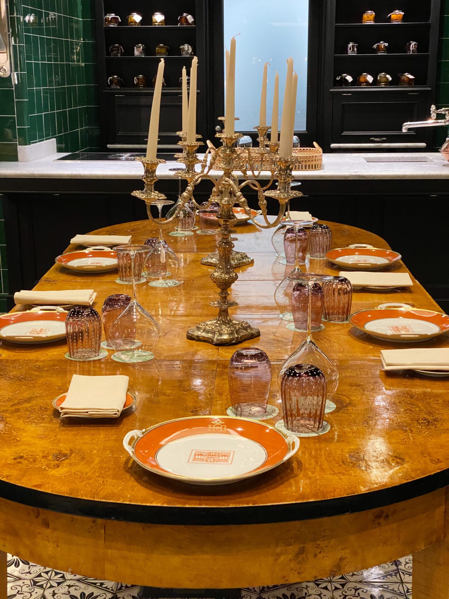 Bright wooden table with glasses and household in front of green ceramic walls and candle holder at the Helvetia & Bristol hotel in Florence Tuscany in Italy