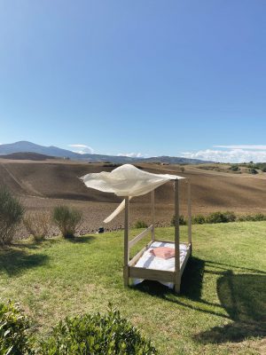 Wooden bed in the middle of a green landscape surrounded by hills in Val D'Orcia Tuscany in Italy