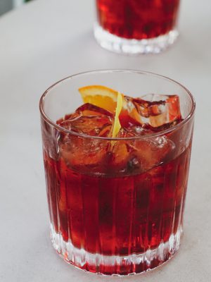 Negroni cocktail in crystal glass with an orange slice over white table in Florence Italy