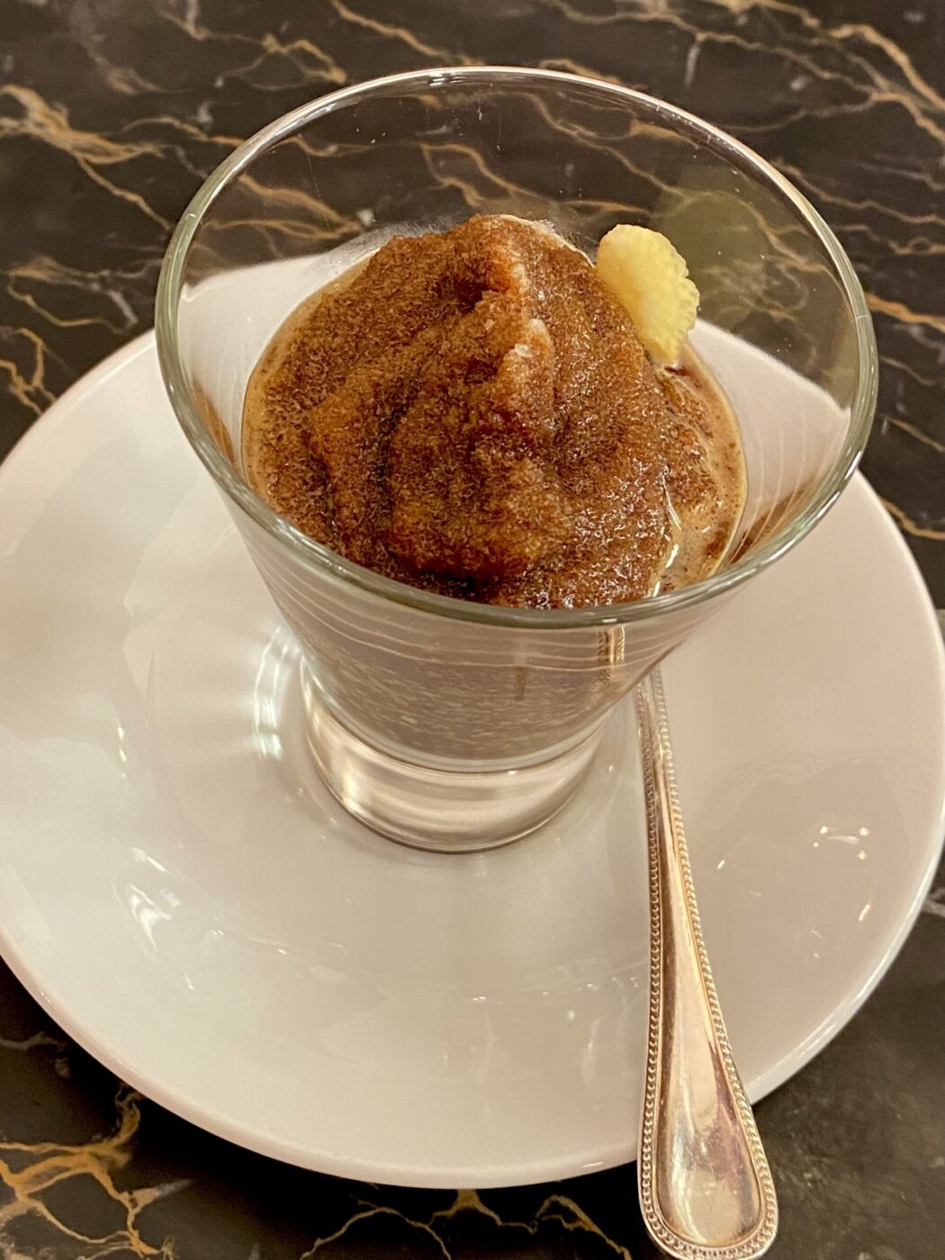 coffee granita served in a small glass cup with a lemon peel