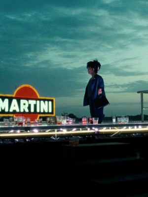 Woman over a bar counter and Martini neon sign with blue cloudy sky in the great beauty film