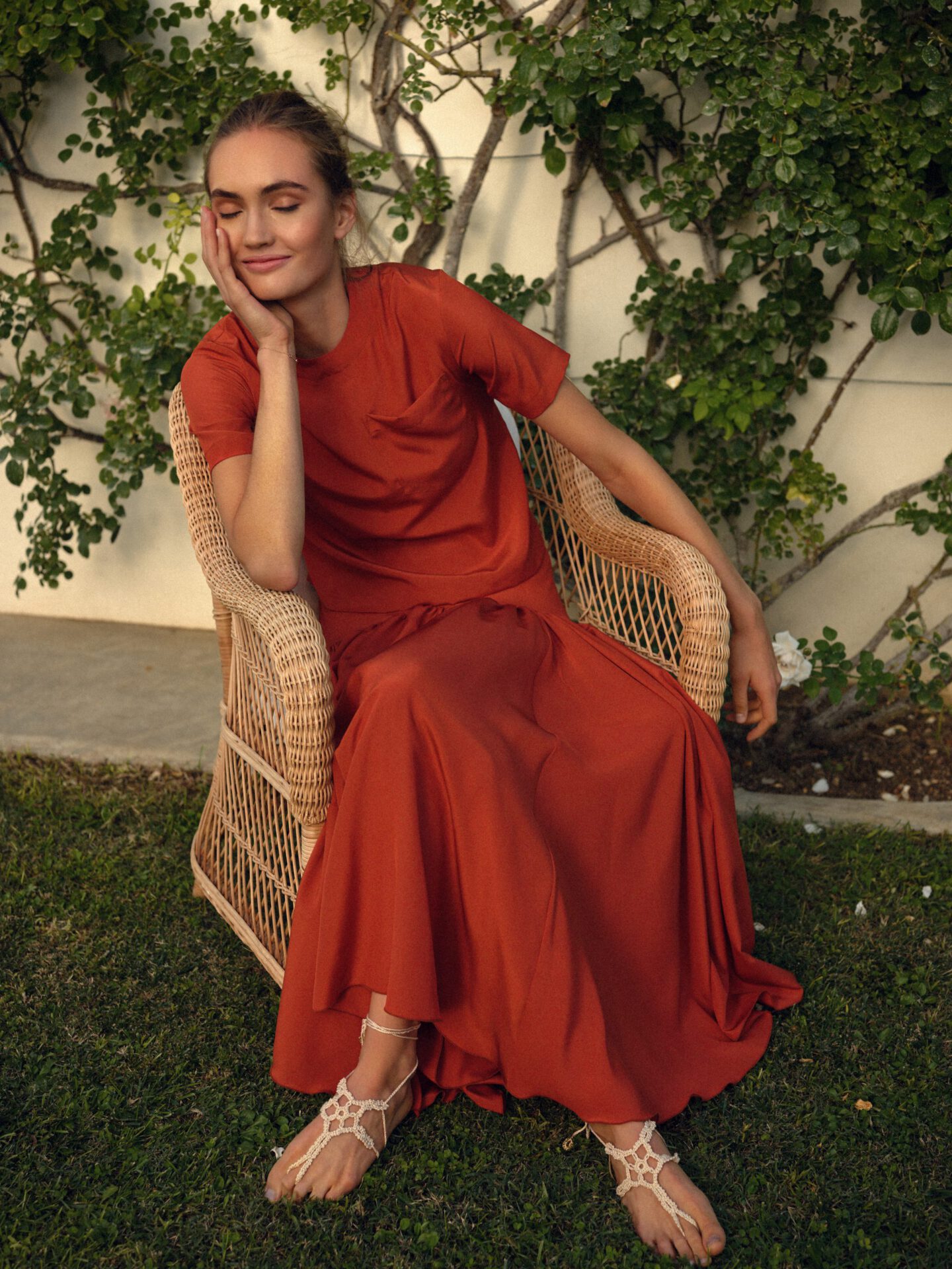 Woman possing with Caftanii red dress and sandals in grass and rustic surroundings in Italy
