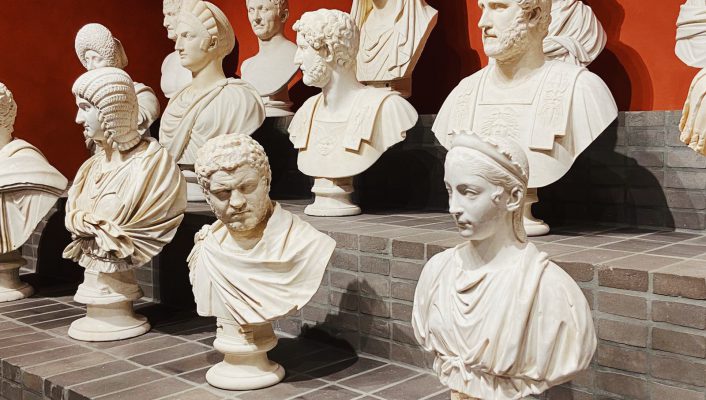 Marble busts of men and women from different ages over a bricked stair shelf with red background at Villa Caffarelli in Rome Lazio in Italy