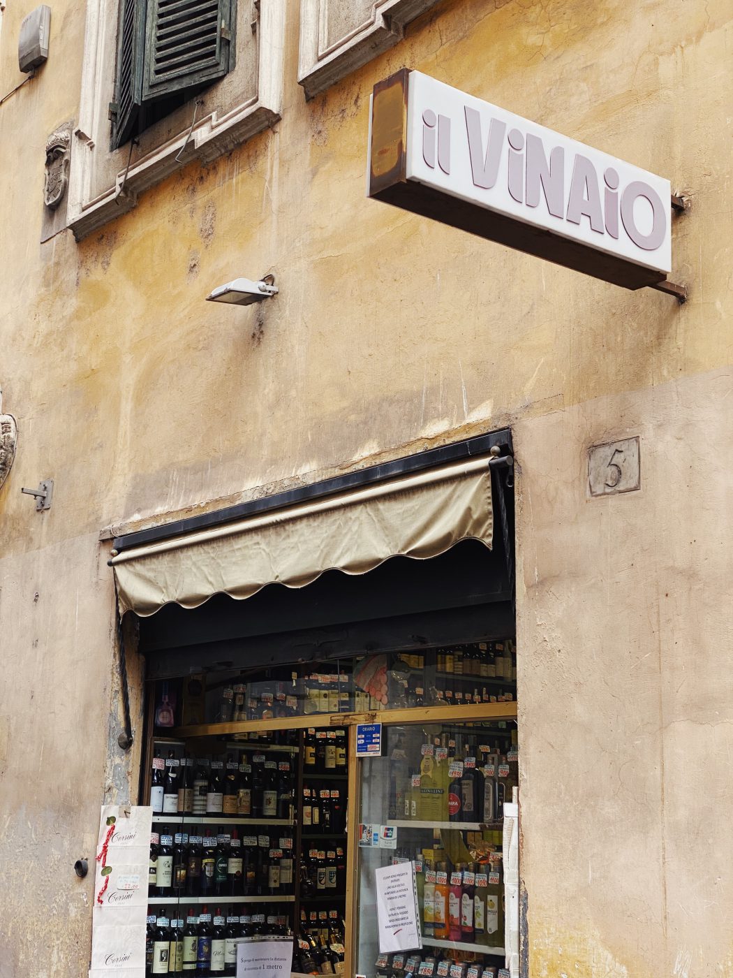 Il Vinaio liquor store with glass shelves filled up with bottles in antique building in Rome Lazio in Italy