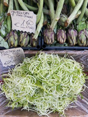 Puntarelle and artichokes over plastic baskets in a local market in Rome Italy