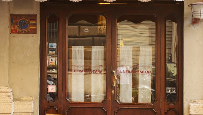 Antique trattoria la Francescana with wooden doors and outside tables with chairs in Rome Lazio in Italy