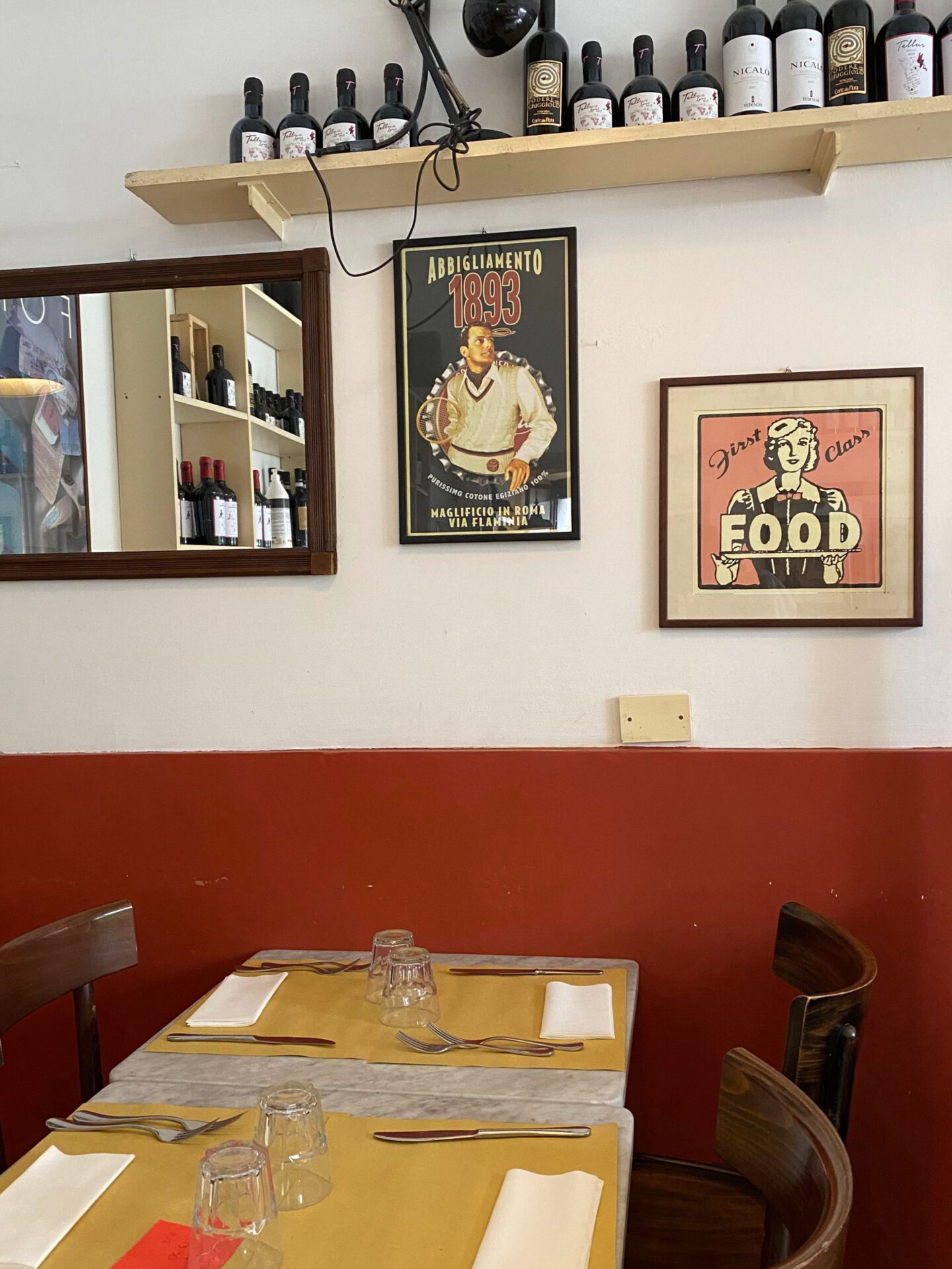 Antique and typical restaurant with wooden tables chair and wall filled with wine bottles and frames at Osteria Chiana restaurant in Rome Lazio in Italy