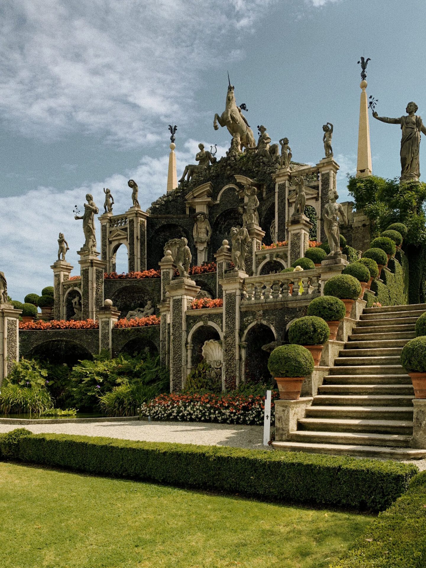 Antique sculptures and columns over a terrace surrounded by plants and geometric fountain in Isola Bella in Lombardy Italy