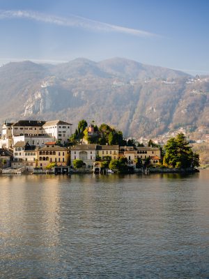Island in the middle of Lake Orta with houses plants with mountains and blue sky background in Piedmont Italy