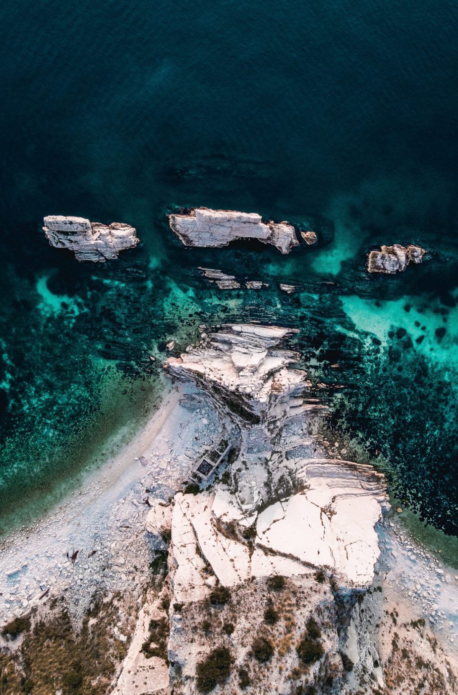 Blue deep sea with huge rocks and plants on the beach of the due sorelle in the marche region in Italy