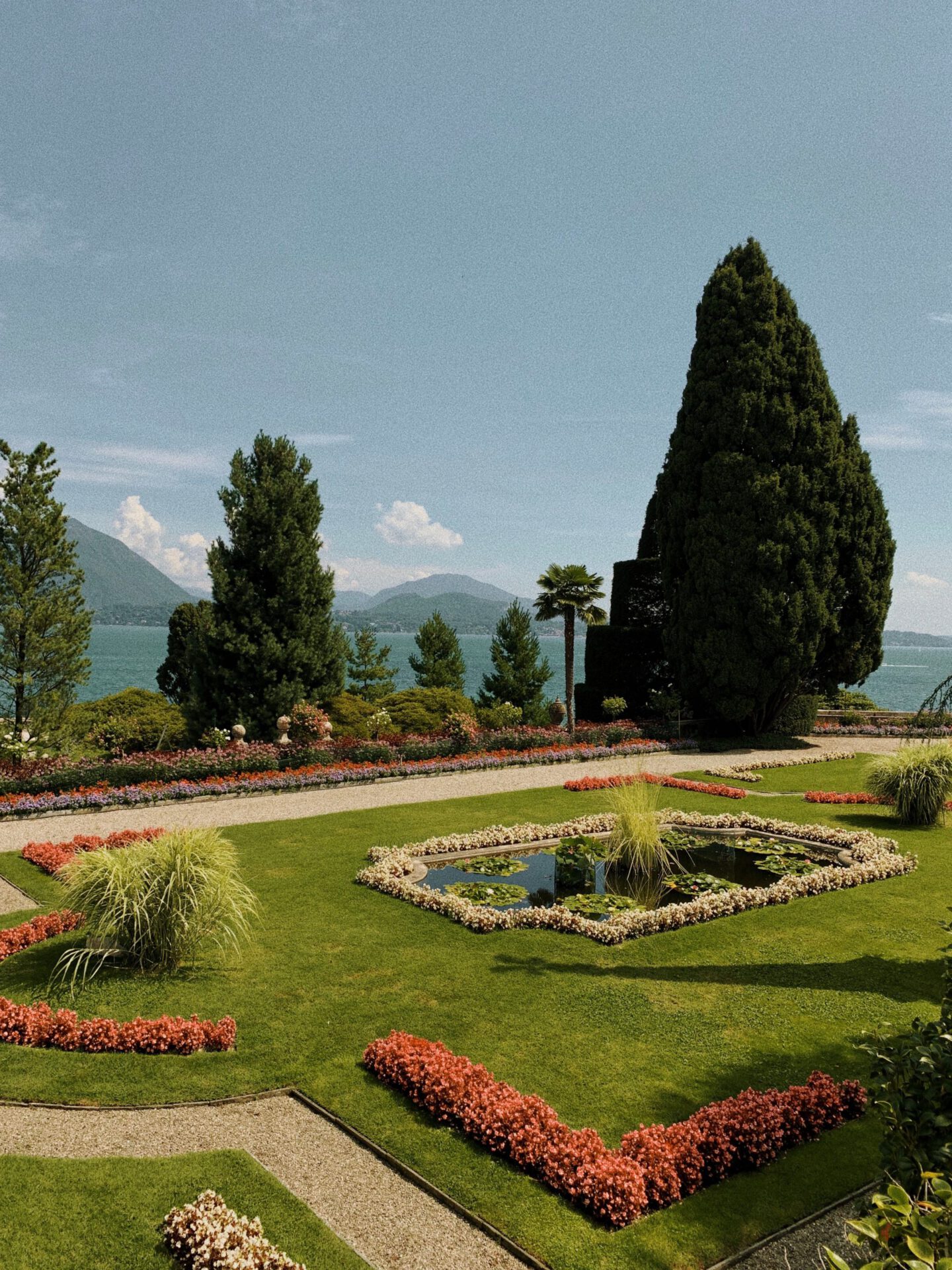 Antique terrace surrounded by plants and geometric fountain with mountains and lake como background in Isola Bella in Lombardy Italy