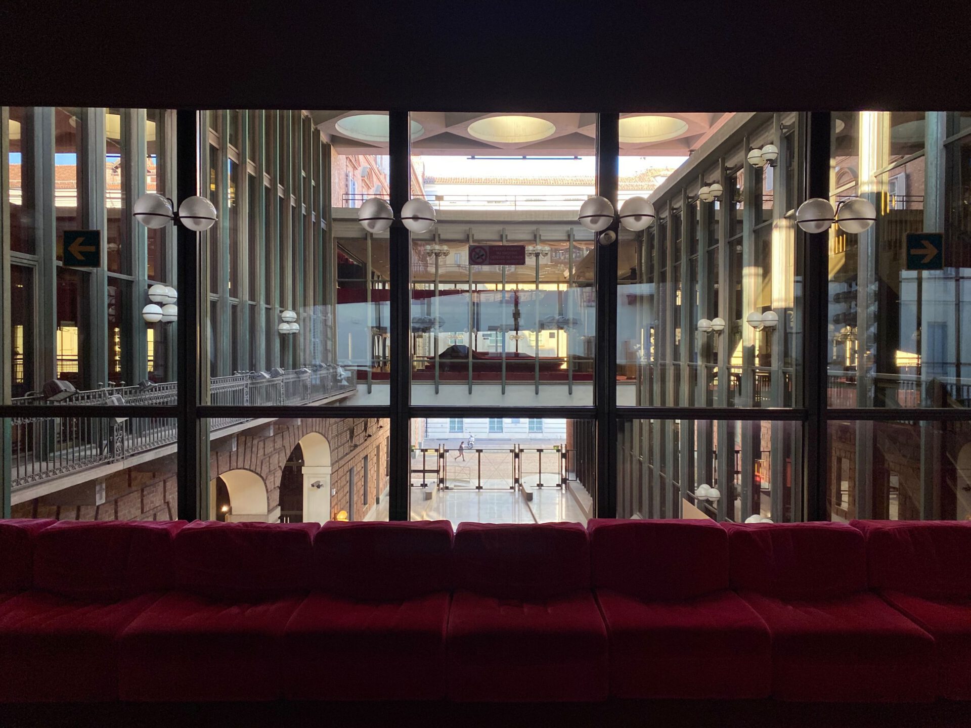 Red furniture and sphere lamps surrounded by windows with columns at Galleria Subalpina in Turin Piedmont in Italy