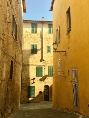 Narrow antique street surrounded by yellow buildings in Tuscany Italy