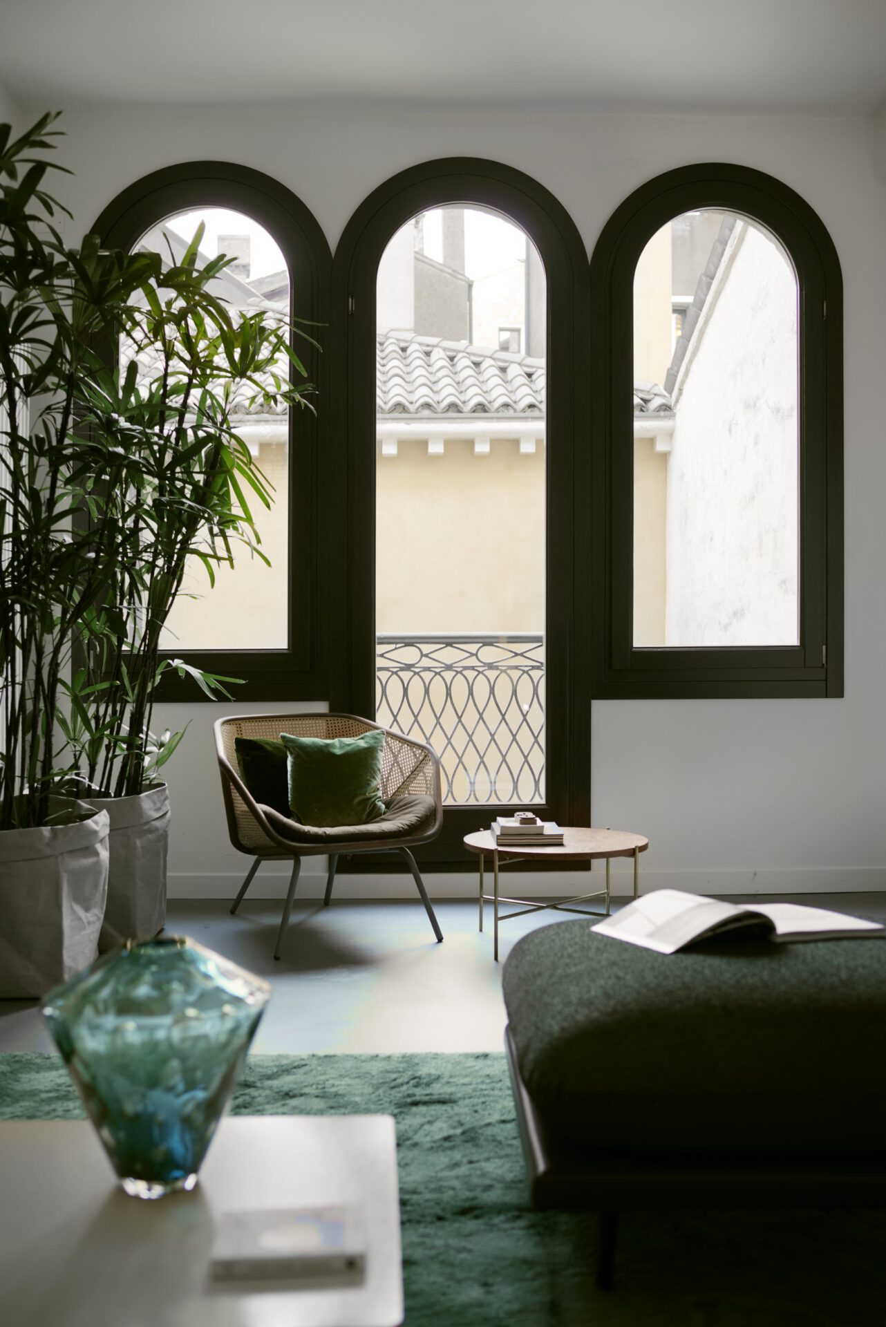 Minimalistic style bedroom surrounded by plants, modern walls and arched windows viewing to antique buildings in Hotel Flora in Venice Veneto in Italy