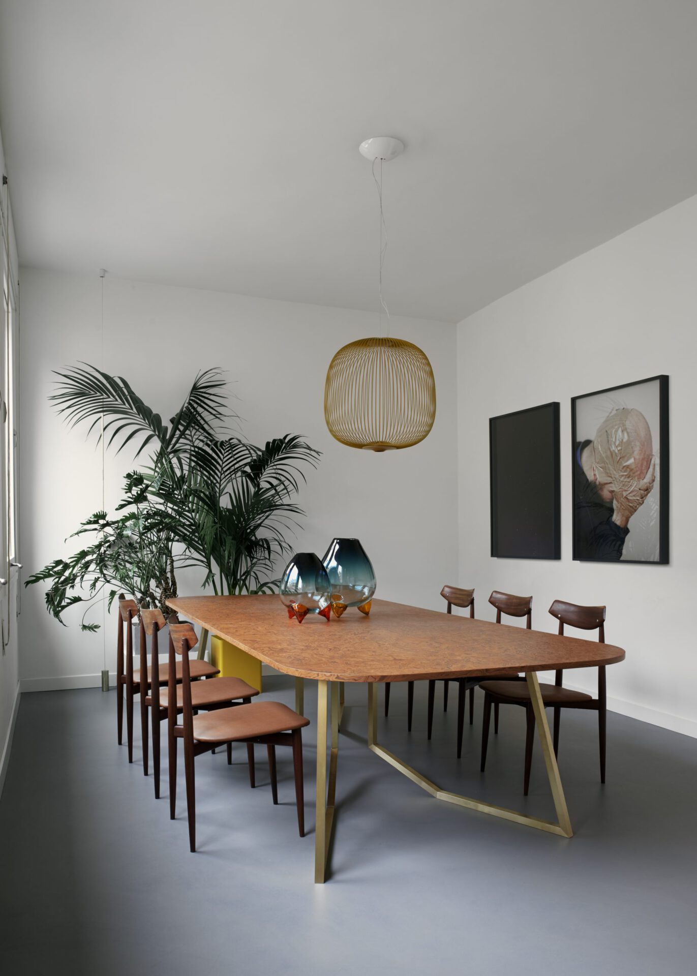 Wooden minimalistic style dinning table surrounded by plants and flower cups in top in Hotel Flora in Venice Veneto in Italy