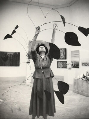 Peggy Guggenheim grey dressed organizing and art piece surrounded by paintings in black and white in Veneto Italy