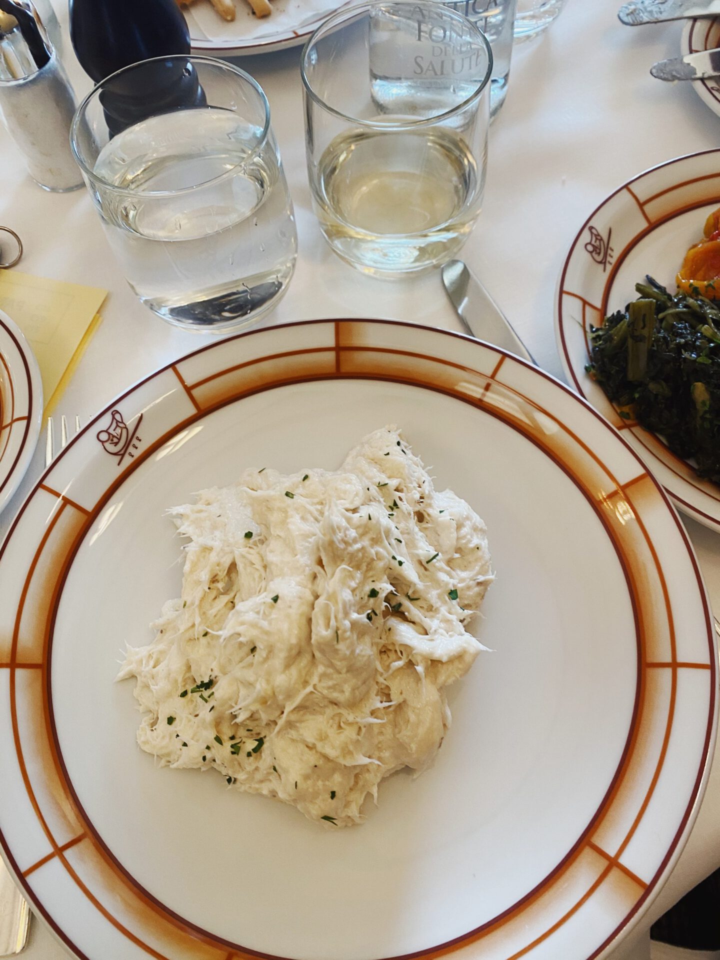 Typical venetian dish Baccala Mantecato over a ceramic white and orange plate in white table with cups and wine in a restaurant in Venice Veneto in Italy
