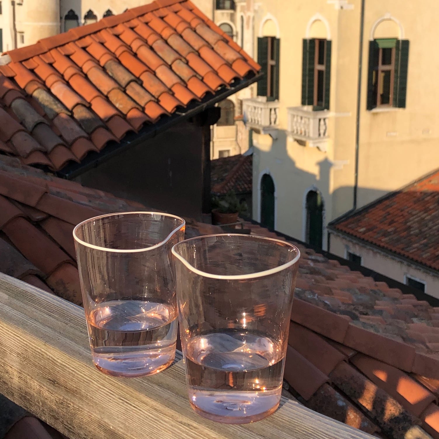 Handmade glass cups with water over typical terrace viewing to antique buildings in Venice Veneto in Italy