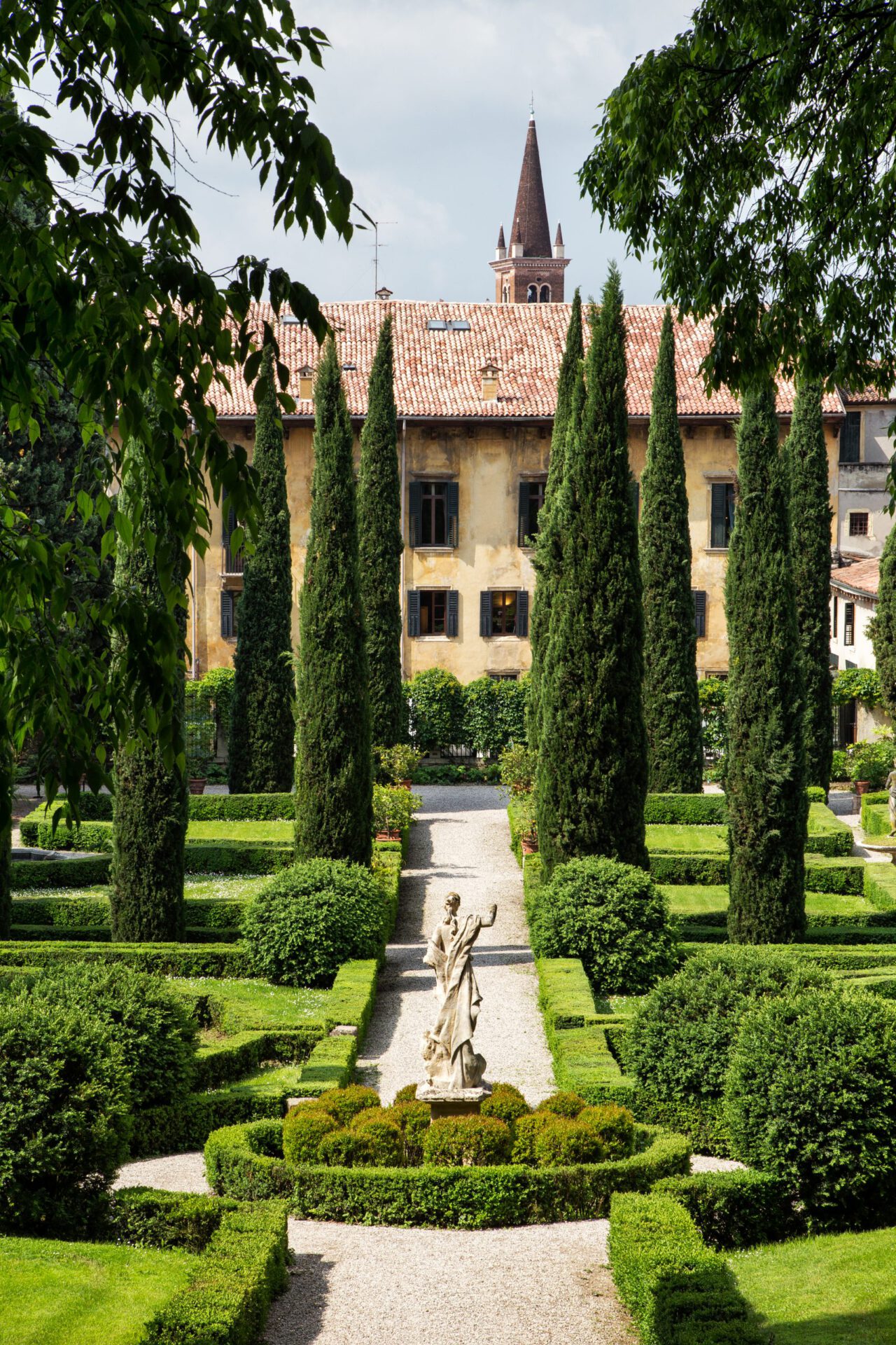 Geometric shaped garden with bushes and tall trees behind a antique building at the Giardino Giusti in Veneto Italy