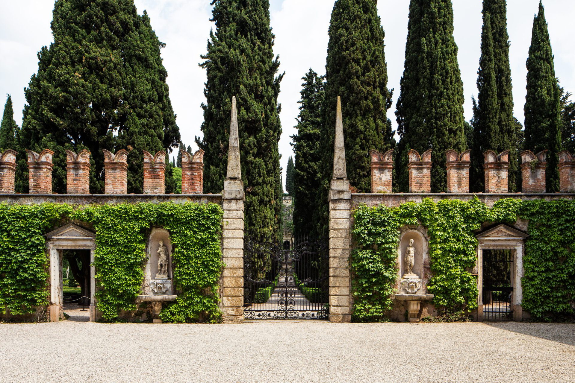 Geometric shaped garden with bushes and tall trees behind a antique building at the Giardino Giusti in Veneto Italy