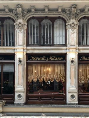 Front view of Baratti & Milano bar in an antique and typical building with wooden like windows and gold colored curtains in Turin Piedmont in Italy