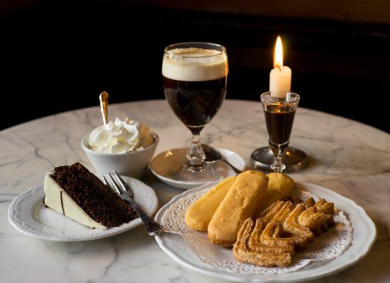 Typical coffee shop's table with bavareisa in a cup, cake, biscotti and lit candle at Caffè Al Bicerin in Turin Piedmont in Italy