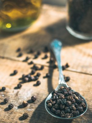Black pepper over spoon over wooden table with olive oil in Italy