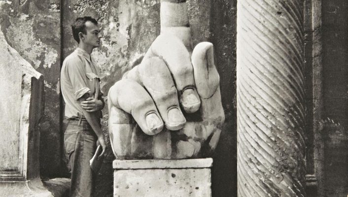 Old picture of Cy Twombly in front of a huge hand shaped sculpture and antique columns in ruins in Rome Lazio in Italy in Black and White