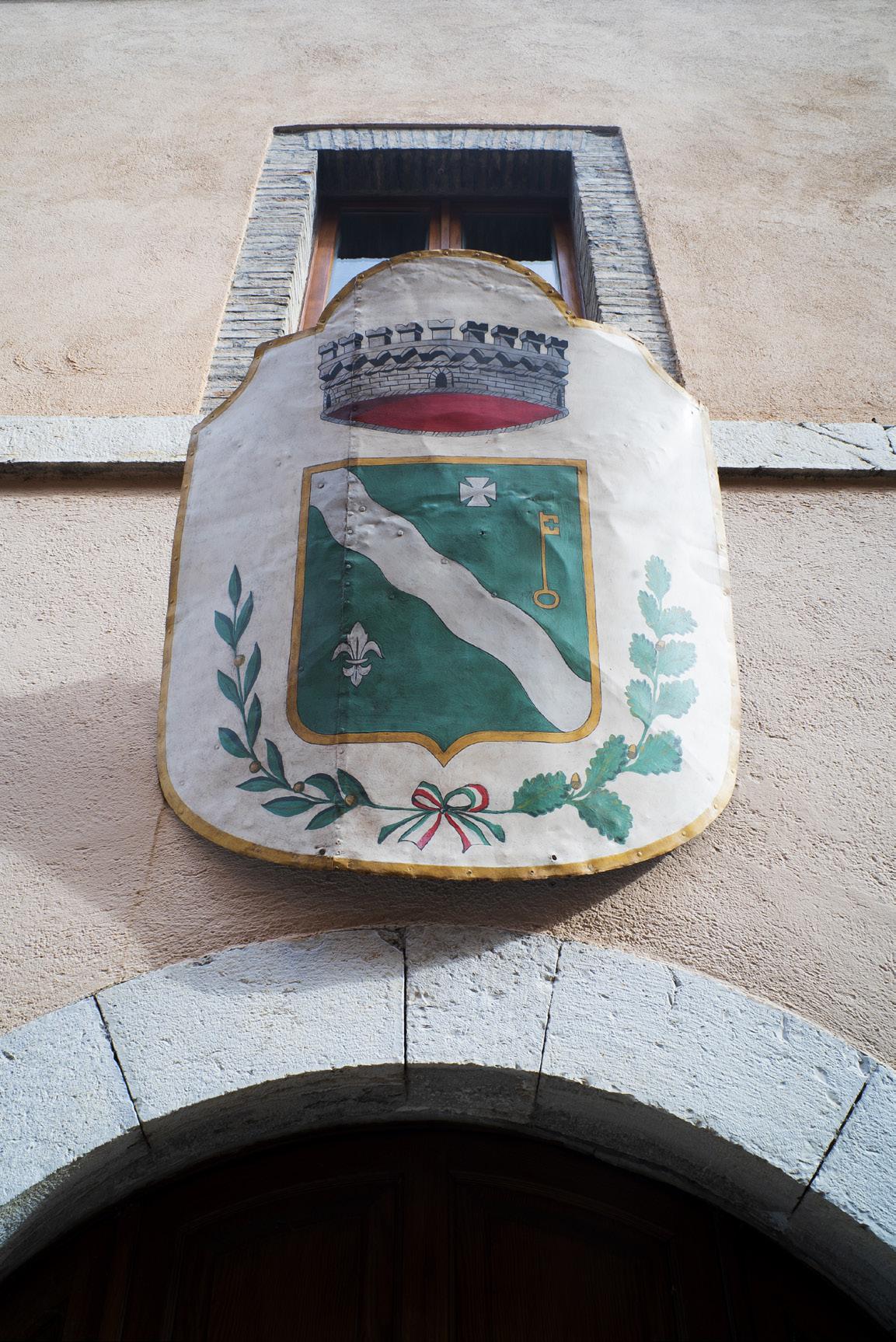 Town's shield hanging from an antique building with wooden doors in Ferentillo Umbria in Italy