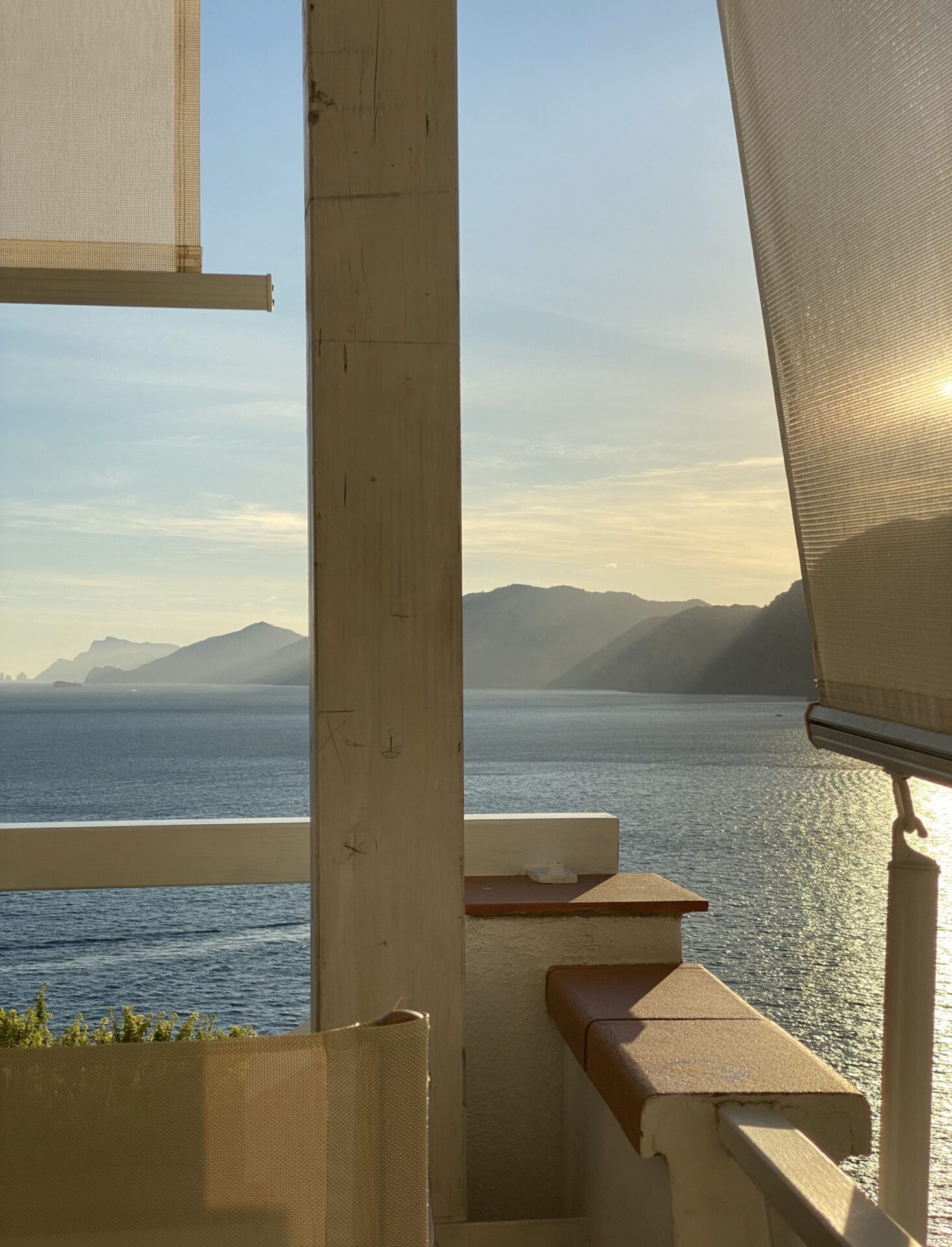 Sea and mountains with sunset landing viewed from a minimalistic style terrace with chairs and shadow panels in Praiano in Campania, Italy